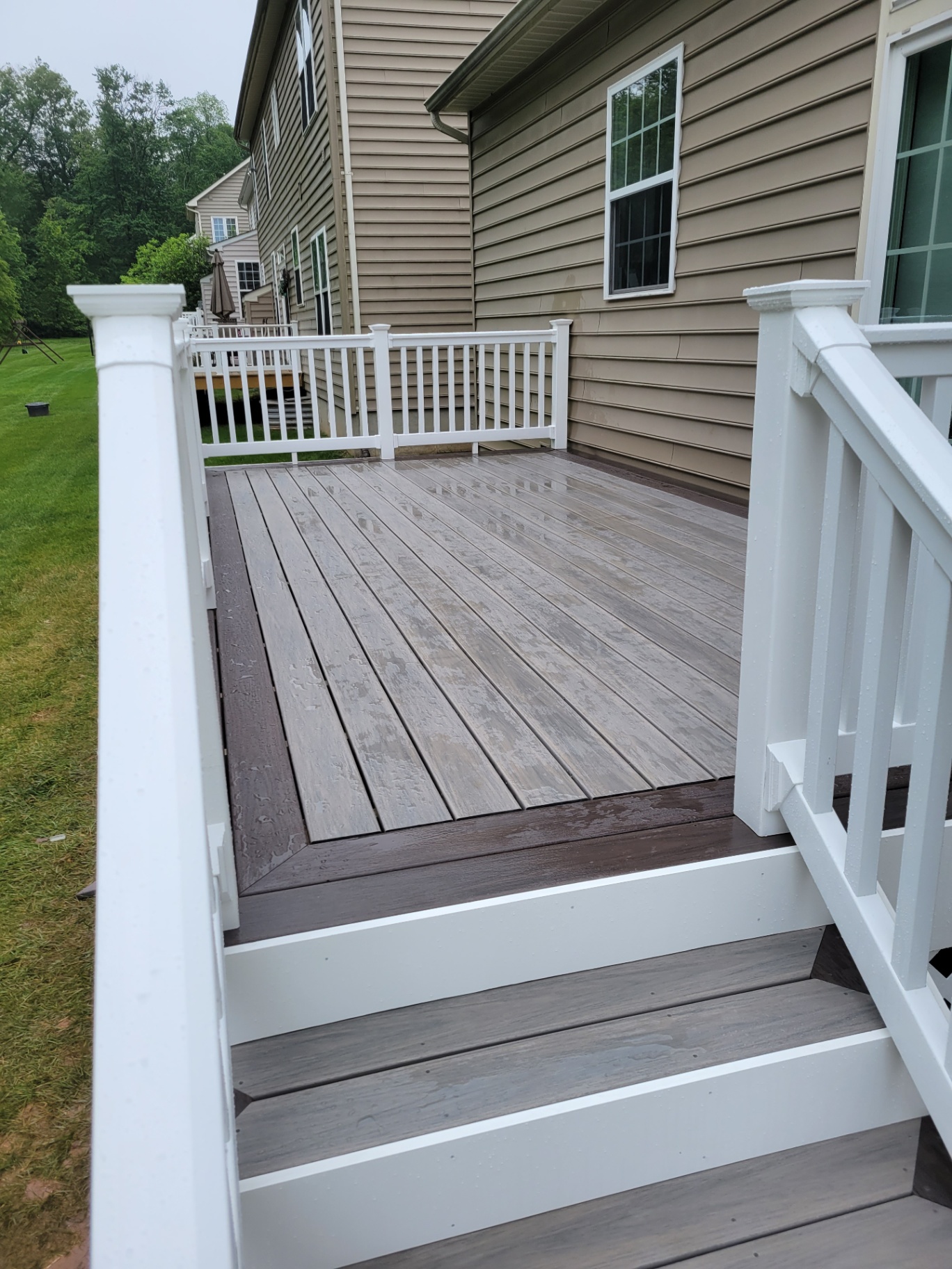 Two-tone composite deck with white railings after rain